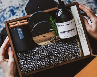 Gift set with 'Savon Blanc' soap, black mug, and other items in a wooden box.