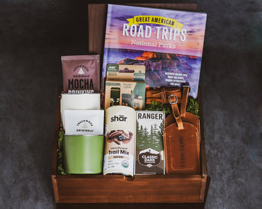 Camping gift set with camp mugs, snacks, and a travel book in a walnut wood gift box