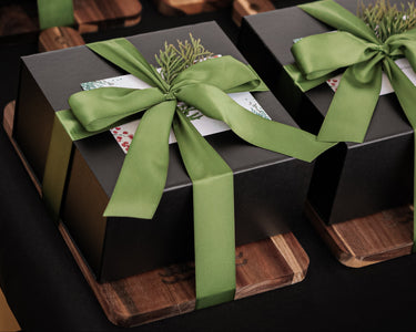 Black boxes with green ribbons on a wooden cutting board