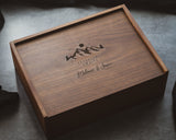 Wooden box with engraved text and design on a gray surface