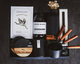 Collection of kitchen items including a bottle of Savon Blanc soap, black containers with wooden handles, and a box on a dark surface.