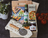Wooden cutting board with pizza ingredients and a cookbook on a dark surface.