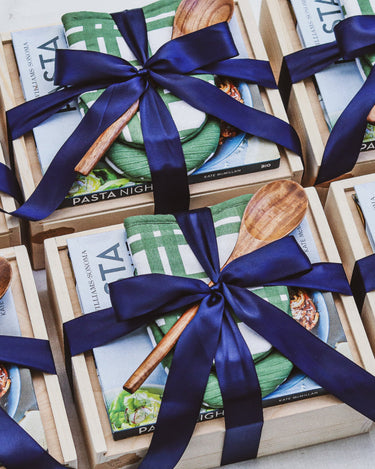 Gift set with cookbooks and wooden spoons tied with blue ribbons