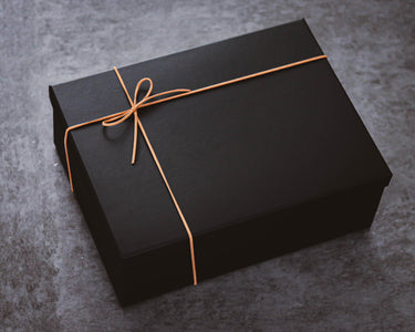 Black gift box with leather twine on a gray surface
