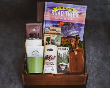 Camping themed gift box with camp mugs, snacks, custom engraved leather travel tags and Great American Road Trips National Parks book