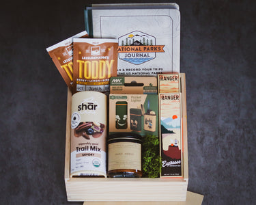 Gift box with snacks, a book, and a jar on a dark background