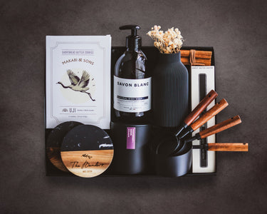 Collection of black and wooden items including bottles, containers, and a card on a dark background